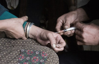 a man injects heroin into the hand of a another