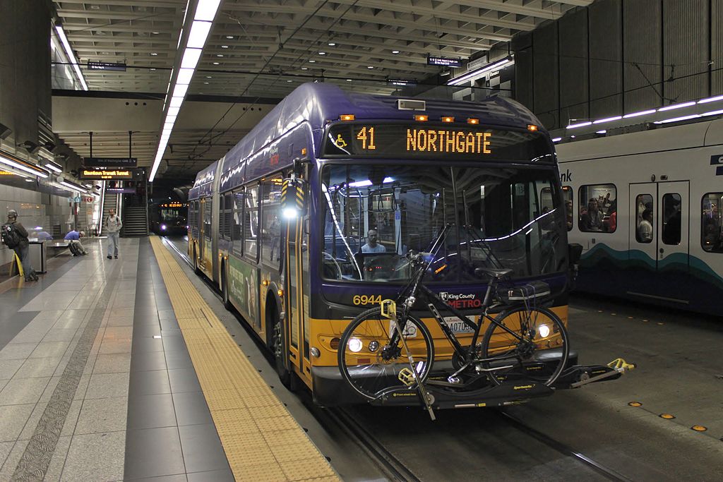 King County Metro 6944, a New Flyer diesel-electric hybrid articulated bus, on route 41 in the Downtown Seattle Transit Tunnel. A second bus on the same route can be seen in the background.