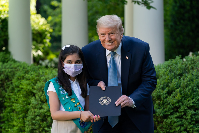 President Trump poses without a face mask with a Girl Scout who is.