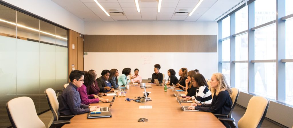 A group of businesswomen in discussion around conference table.