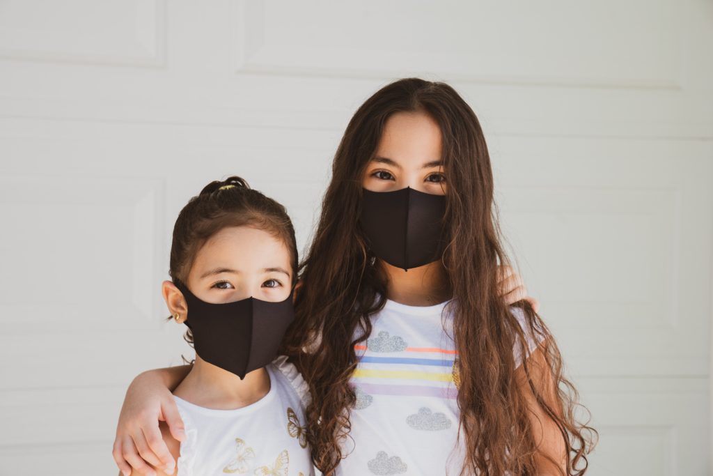 Two young girls wearing masks.