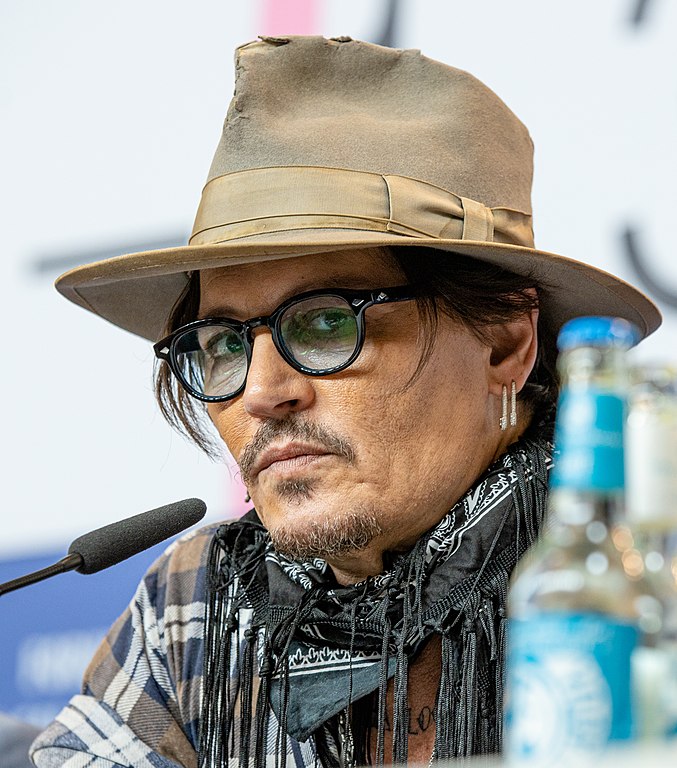 Actor Johnny Depp, wearing a hat, scarf and glasses and scowling at the Berlinale 2020. Photo by Harald Krichel.