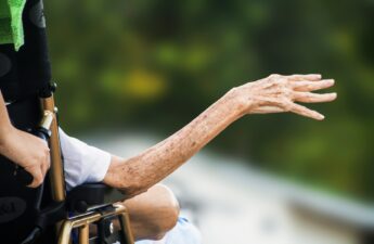 Photo of the arm of an elderly man sitting in a wheelchair.