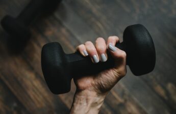 A hand holding up a small barbell.