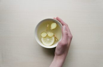 A photograph of a woman's hand cradling a cup of ginger tea.